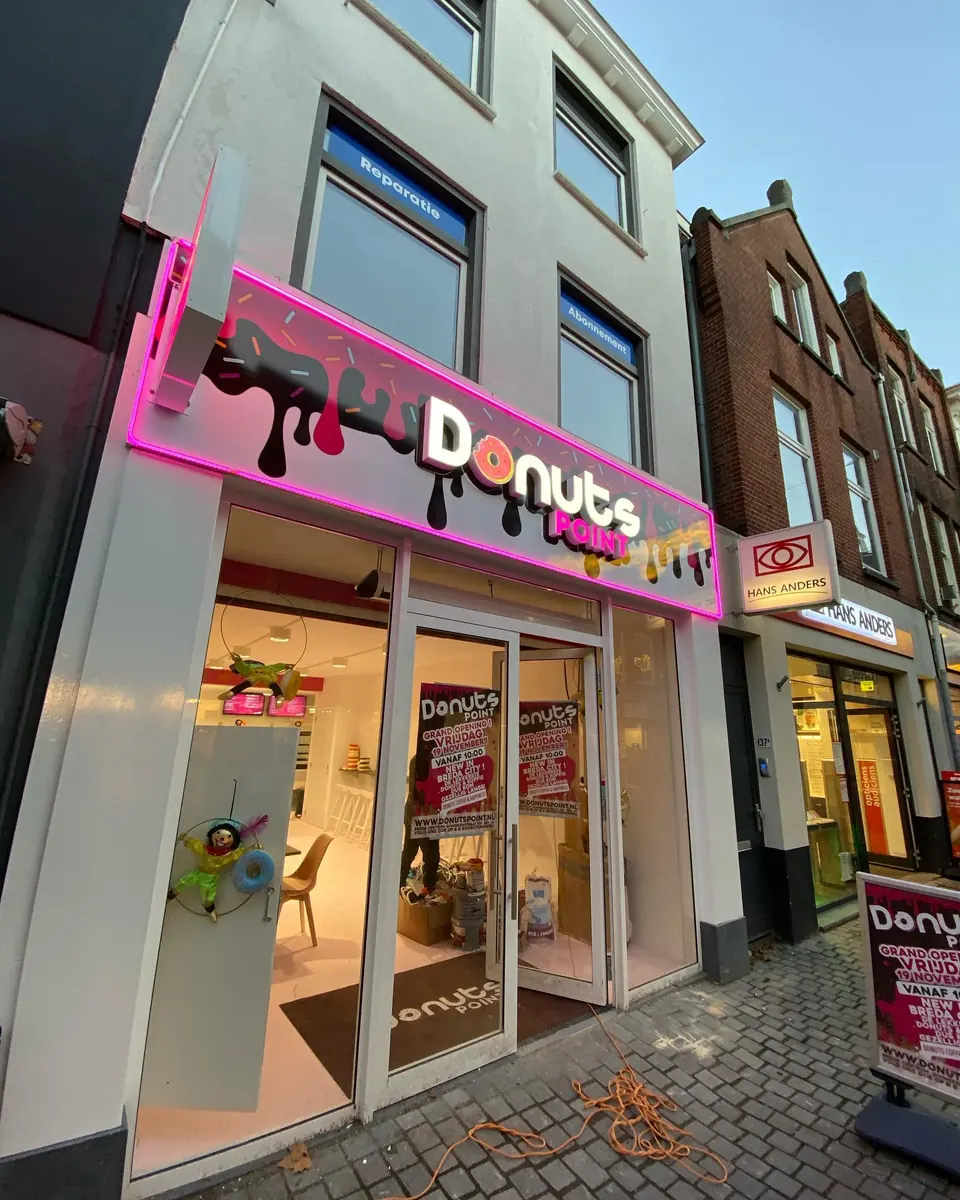 Gevel van Donuts Point met roze dibond, doosletters en uithangbord